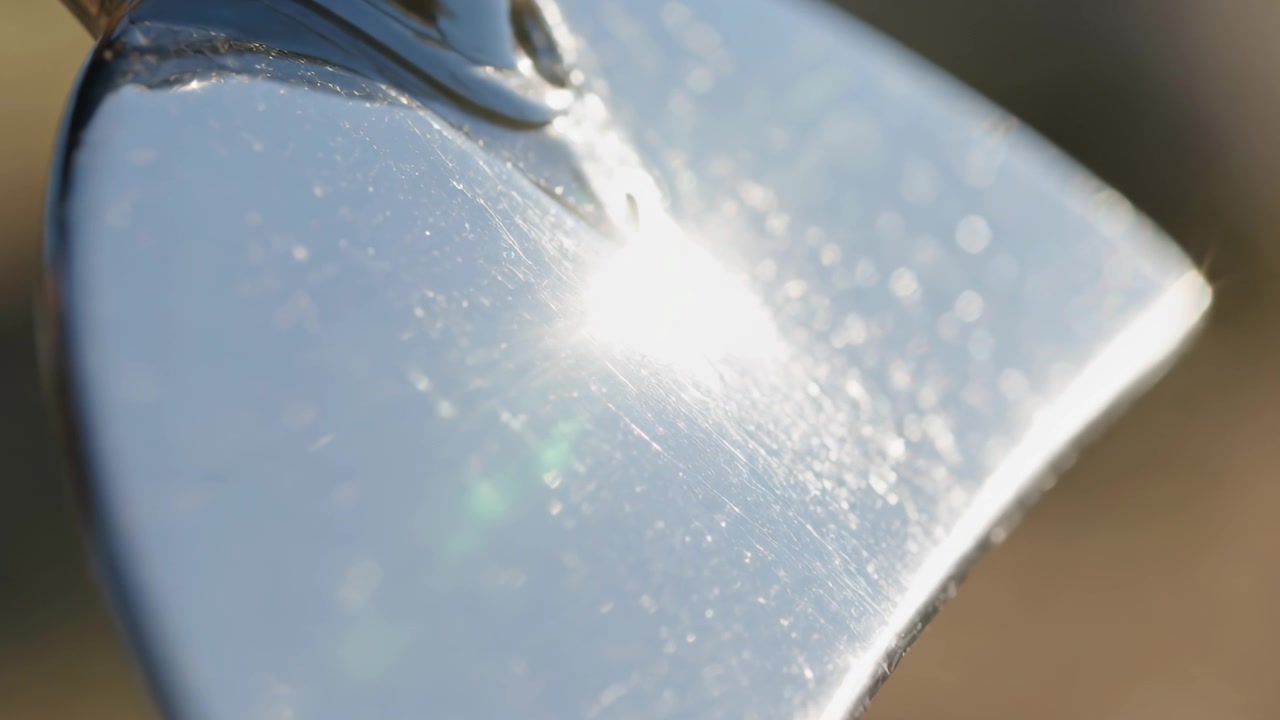 庭で太陽に向かって傾けられた、光沢のある金属製こてがキラキラと輝き、傷やきらめきが露わになる。