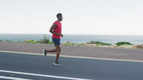african american man exercising outdoors running on a coastal road