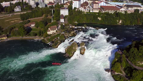 tracking shot of a red tourist boat fighting the roaring waterfall rheinfall at schaffhausen in switzerland