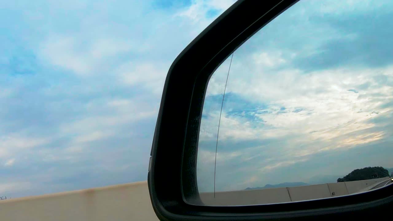 View in rear mirror from car on highway, personal transportation, car driving on motorway along concrete wall