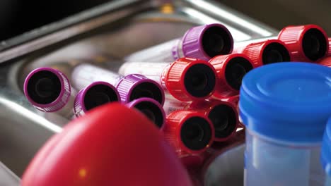 toma de primer plano de los tubos de recogida de sangre, cinematográfica de mano capturando un lote de tubos de recogida de muestras no utilizados, tapas rojas y tapas púrpuras, tubos de sangre, donante de sangre