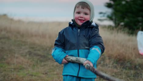 young boy playing with a stick in a small stream out in the country