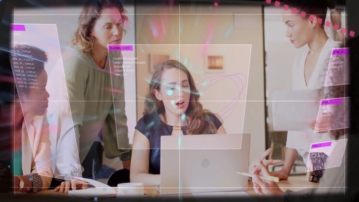 Seated woman looking up and typing laptop as colleagues sharing docs, driving business UI overlays