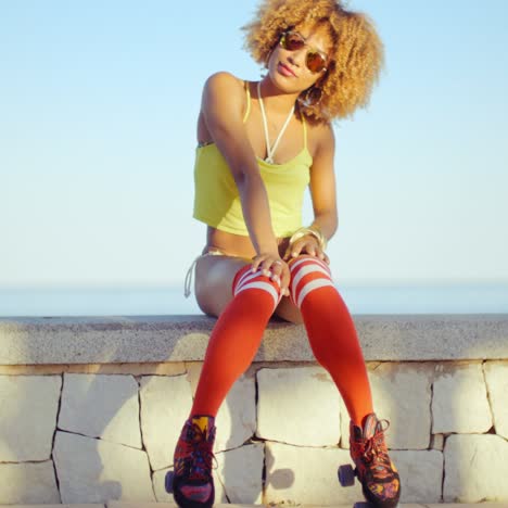 sexy skate girl sittin en la pared en el paseo marítimo