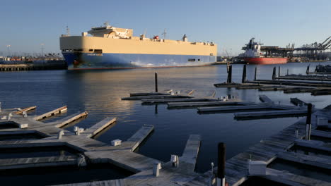 large cargo ship docked in a busy harbor with empty boat slips