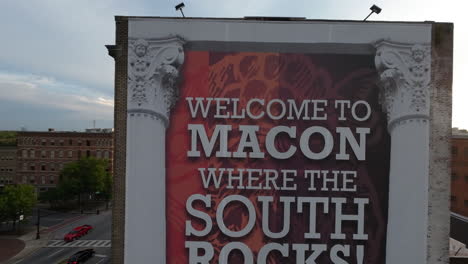 Drone-camera-rises-up-to-reveal-Welcome-to-Macon-Where-The-South-Rocks-Mural-on-downtown-building-revealing-late-afternoon-sun