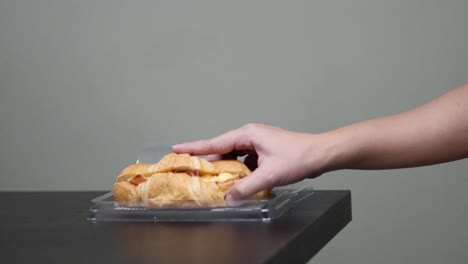 hand removes cover, picks up a croissant