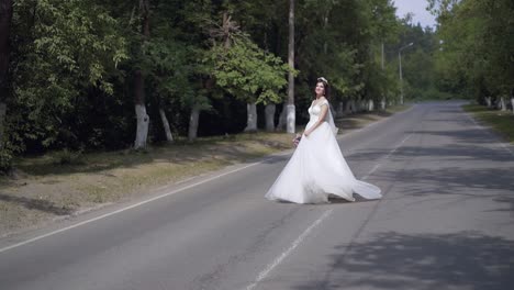 slow motion bride in long white dress dances on road