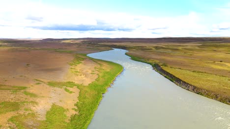 aerial establishing shot of a large river running through the icelandic countryside