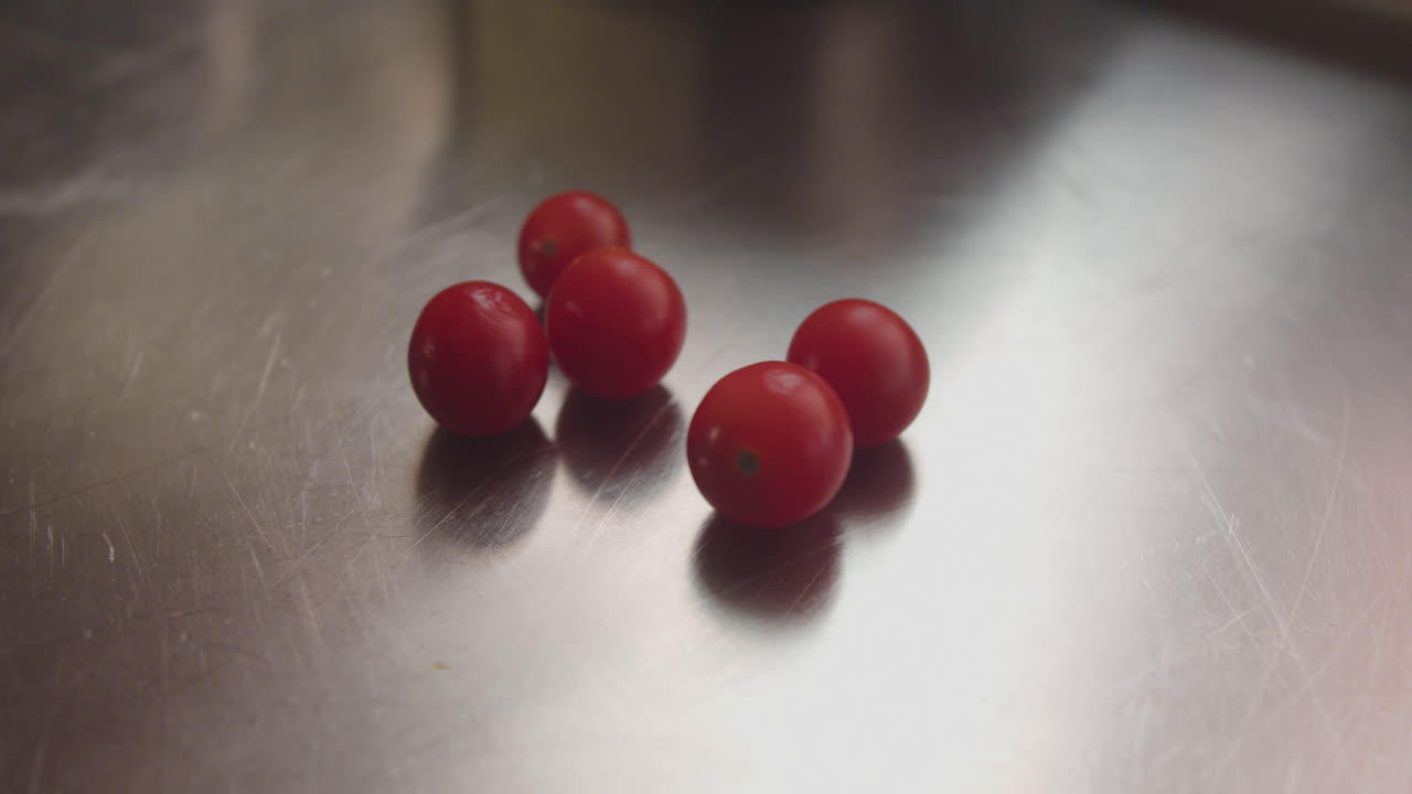 Hand placing and showing fresh cherry tomatoes on a metallic surface
