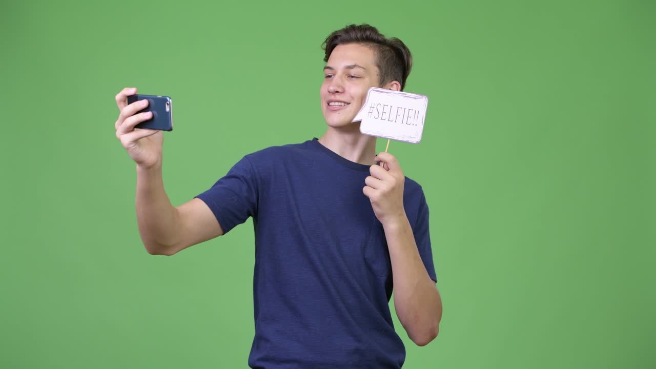 Young handsome teenage boy taking selfie