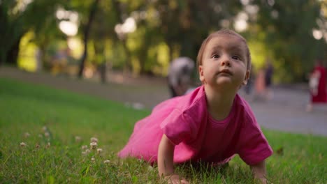 una niña linda arrastrándose por el césped en un parque