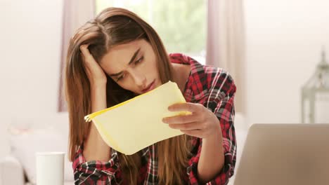 una morena molesta con una calculadora pagando cuentas