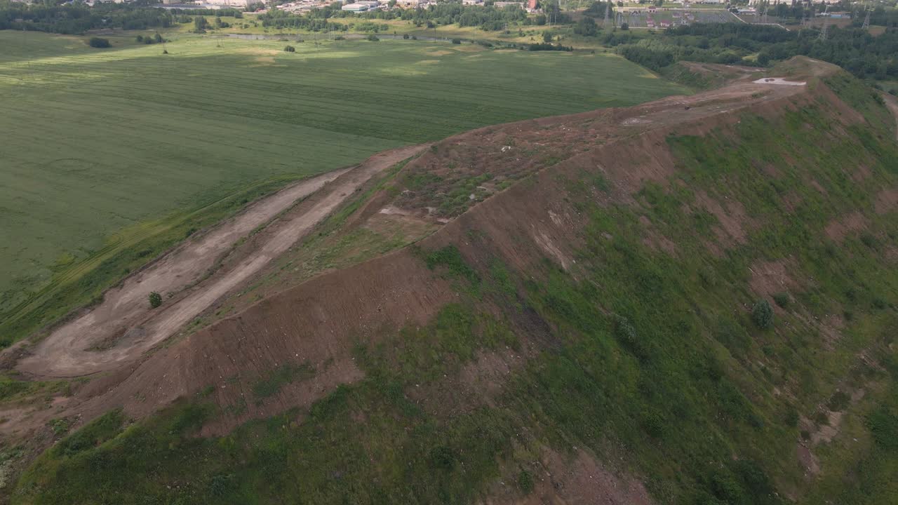 Household waste landfill. Closed for processing. Environment protection. Close-up shot. The city is visible on the horizon. Close-up shot. Aerial photography