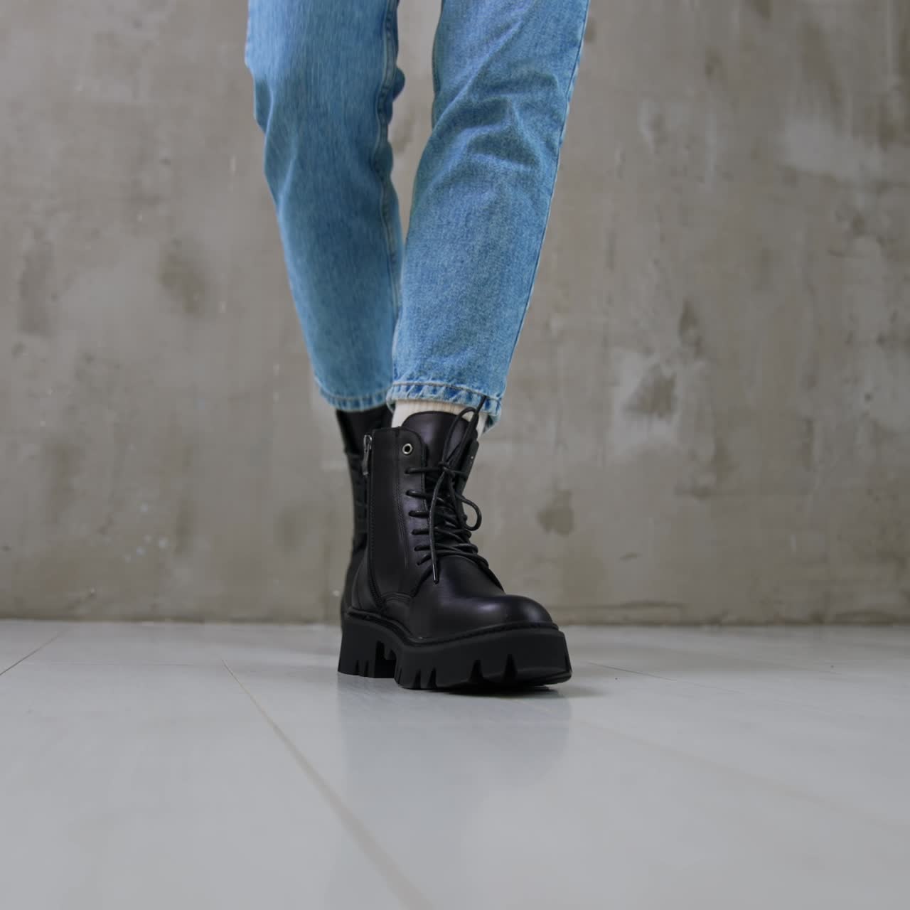 Model wearing jeans and white socks demonstrates black boots. Convenient cold weather footwear for females close up