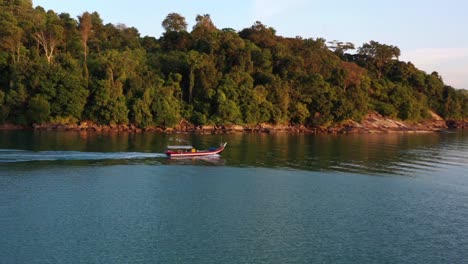 Tiro-De-Seguimiento-Aéreo-Que-Captura-Un-Barco-De-Pesca-Tradicional-En-Góndola,-Navegando-Hacia-El-Océano-Para-Pescar-En-La-Hermosa-Hora-Dorada-Del-Atardecer,-Isla-Langkawi,-Malasia,-Sudeste-De-Asia