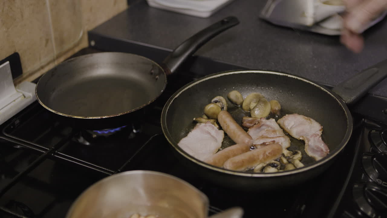 Cooking a breakfast with sausage, bacon, mushrooms and egg