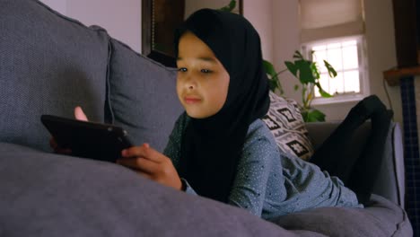 Mädchen-Im-Hijab-Mit-Digitalem-Tablet-Im-Wohnzimmer-4K