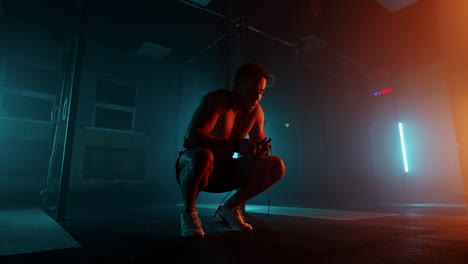 recuperate after a workout in the gym. a tired man wipes his sweat and prepares for a victorious dash. blue and orange color.