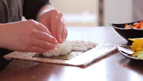 making sushi at home kitchen. woman hands rolling homemade sushi.