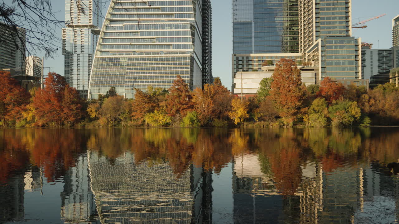 hermosos árboles y edificios del centro de la ciudad con reflejo en el agua del lago durante el atardecer de otoño con hermosos colores en las hojas de los árboles