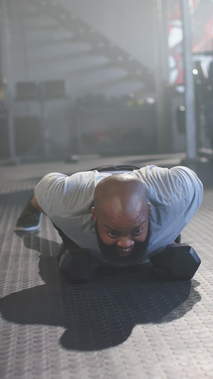 Video verticale: Uomo che si prepara, fa flessioni e rematore con un braccio con manubri esagonali durante l'allenamento in palestra