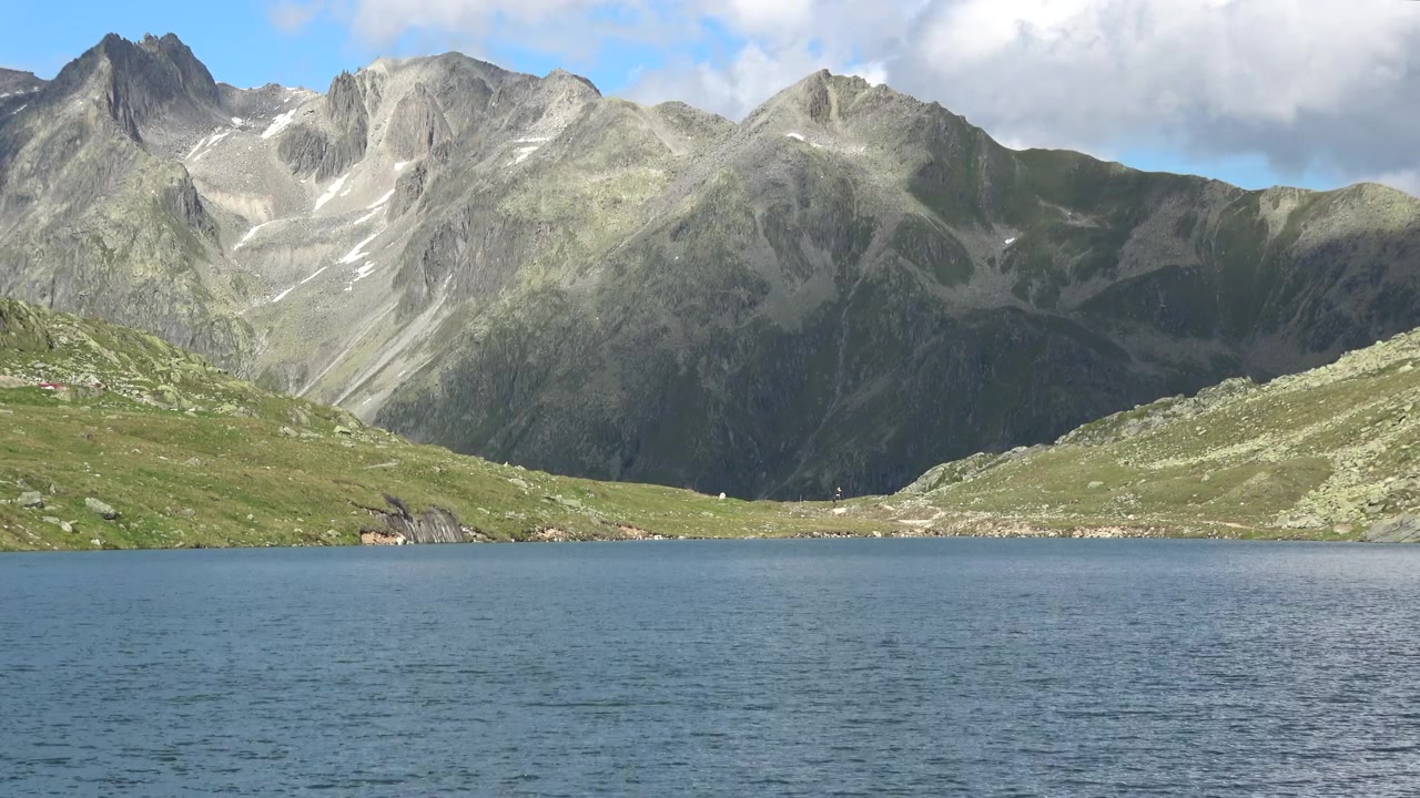 Panorama di un lago alpino soleggiato e della vetta di una montagna nelle Alpi svizzere