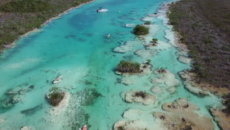 aerial view of blue water paradise in bacalar mexico - boats are sailing in the water channel