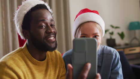 Fröhliche-Gruppe-Verschiedener-Freunde,-Die-Ihr-Smartphone-Für-Videoanrufe-Auf-Der-Weihnachtsfeier-Nutzen