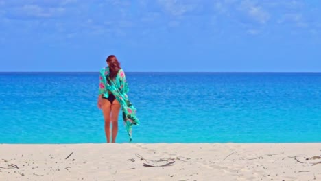 woman walks with floral blouse on windy beach, slow motion