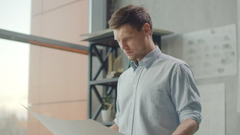 hipster engineer works with blueprint. shoot from above. young architectural engineer working in office. bearded man makes sketches. loft style minimalistic interior drawings on the table