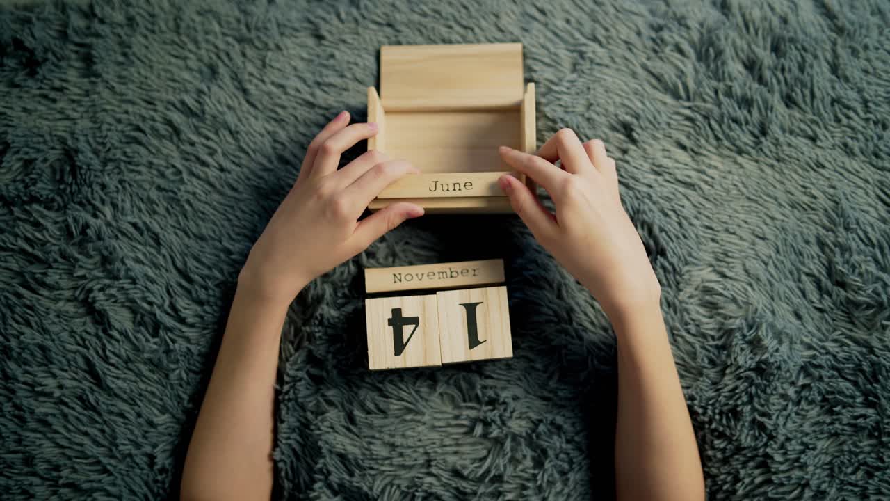 Boy changing wooden calendar block. Date on wooden cube calendar