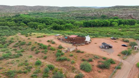 Aerial-push-in-tilt-down-above-round-corral-pen-holding-horses-in-rainy-desert-southwest