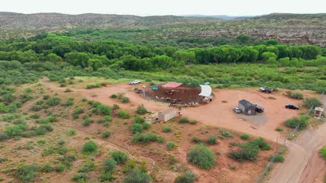 aerial push in tilt down above round corral pen holding horses in rainy desert southwest