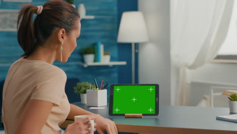 Caucasian-female-looking-at-tablet-computer-with-mock-up-green-screen