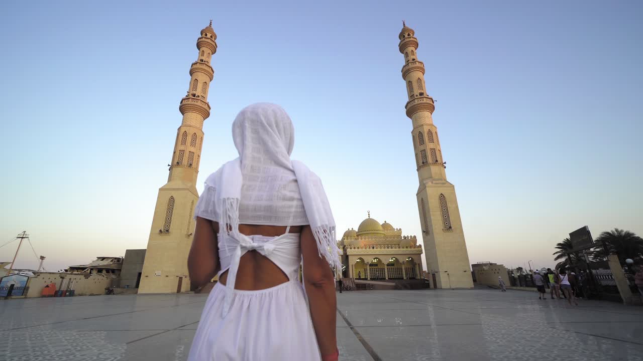 mujer musulmana con hijab de pie frente a la mezquita de el mina masjid en hurghada