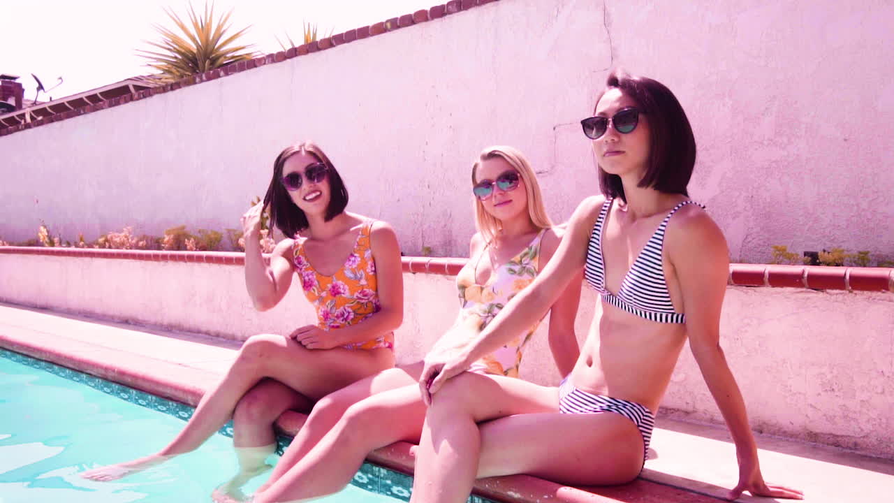 Female friends enjoying the company of each other while sitting poolside