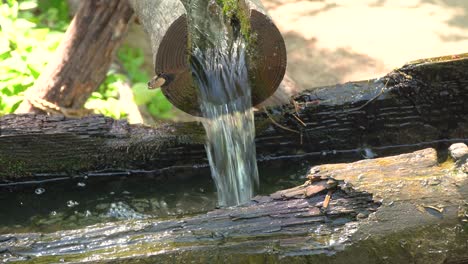 Wasser,-Das-Durch-Offene-Holzrohre-Fließt,-Die-Alte-Heruntergekommene-Hölzerne-Wassermühle-Zum-Mahlen-Von-Weizen-Und-Reis-Im-Koreanischen-Volksdorf-Yongin-City,-Korea-Nahaufnahme,-Füllen