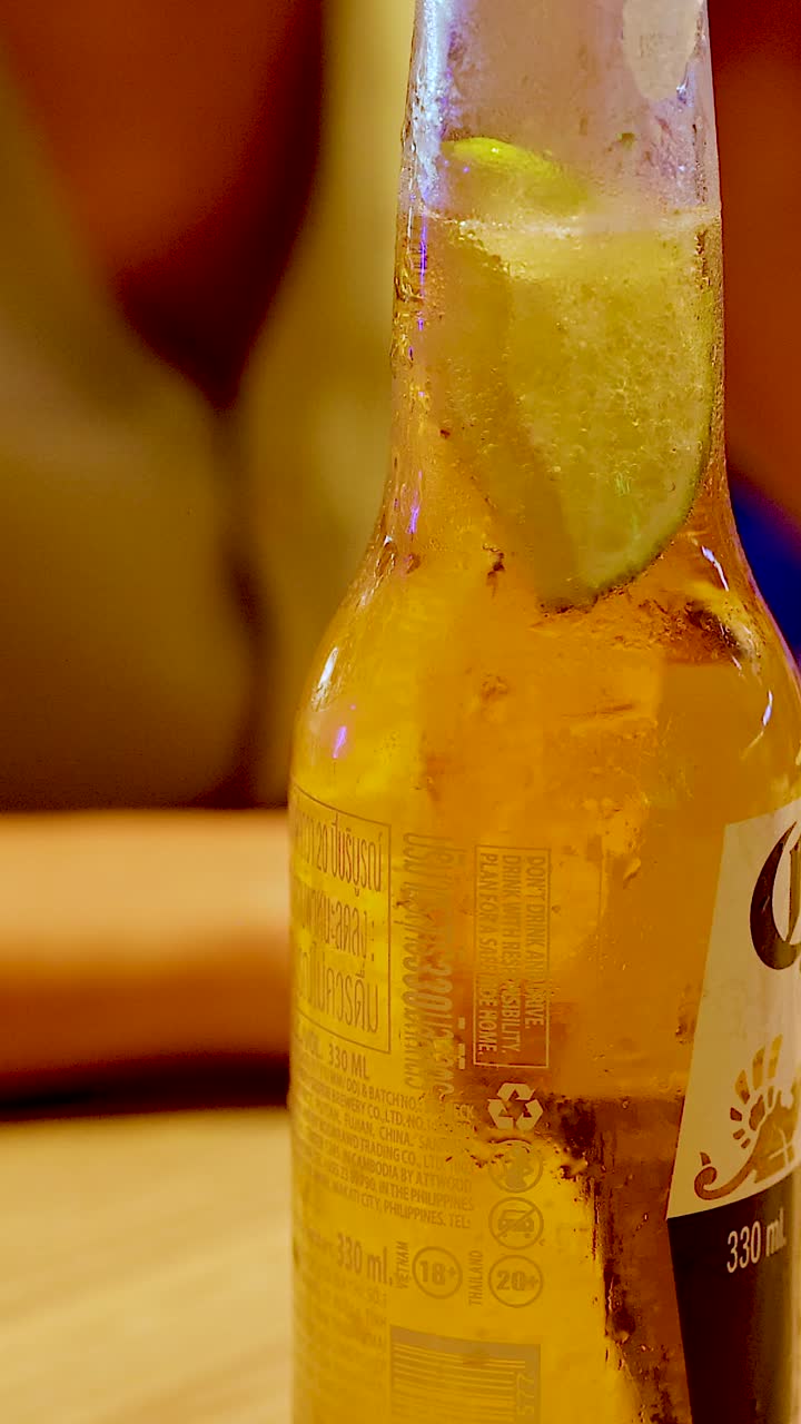 Una toma vertical en primer plano de una botella de cerveza fría con una rodaja de lima fresca en su interior.