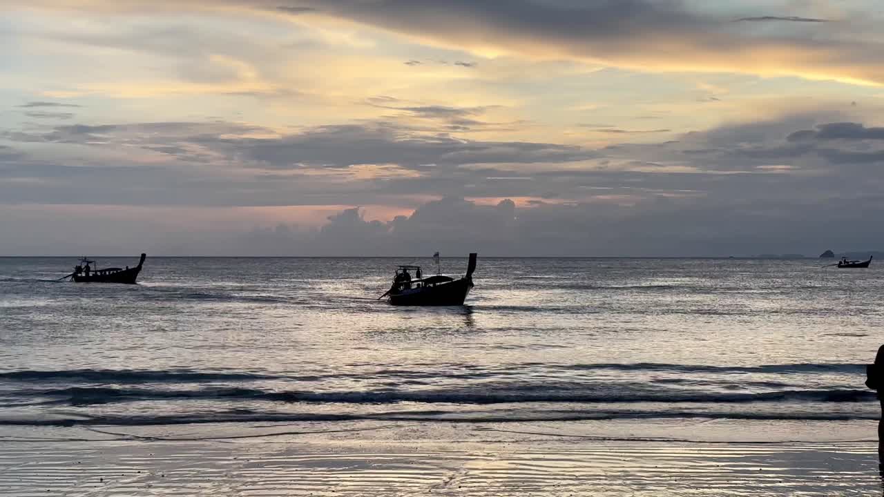 Boats approaching the shore at sunset, preparing to anchor and bring people ashore