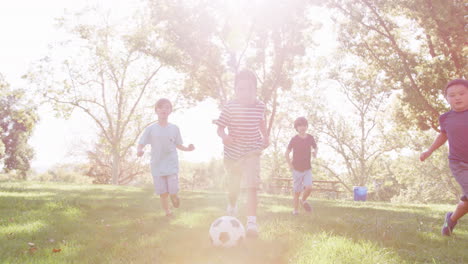 Group-Of-Young-Boys-With-Friends-Playing-Football-In-Park-Shot-In-Slow-Motion