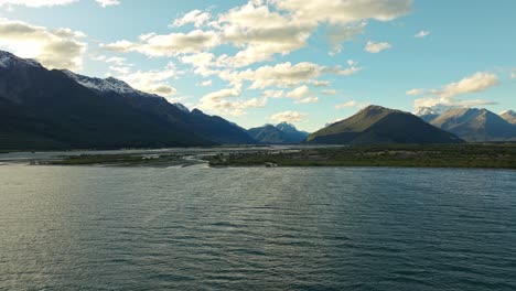 establecimiento aéreo panorámico de luz dorada que se refleja a través de las nubes en el lago wakatipu con tierras bajas de glenorchy detrás