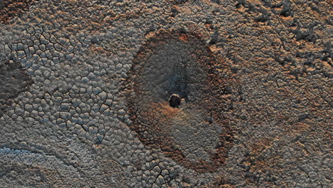 boiling mud volcanoe pond with colorful textures and pattern around