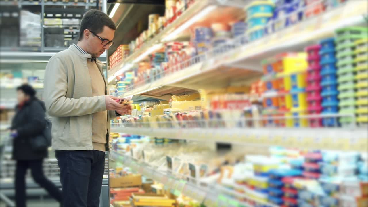 한 남자 가 식료품 가게 에서 유제품 을 구입 하고 있다