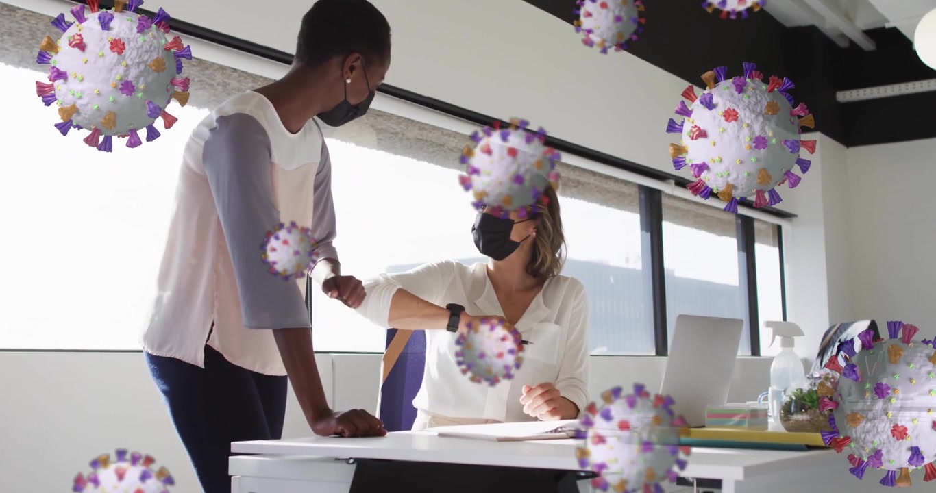 Masked colleagues reviewing papers in office as floating virus graphics initiating elbow bump