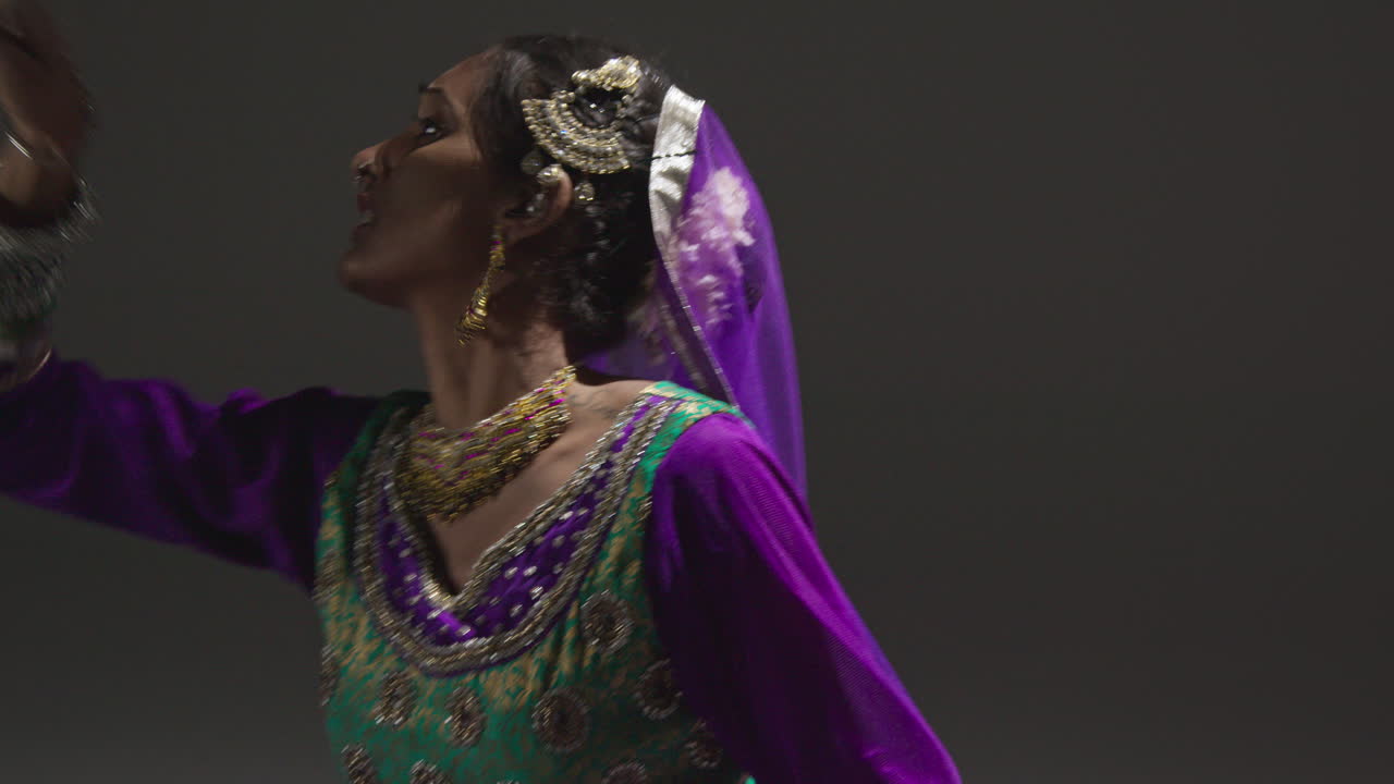 primer plano de una bailarina de kathak femenina realizando un baile vestida con un vestido tradicional indio sentada en el suelo en el centro de atención