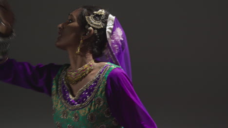 Close-Up-Of-Female-Kathak-Dancer-Performing-Dance-Wearing-Traditional-Indian-Dress-Seated-On-Floor-In-Spotlight