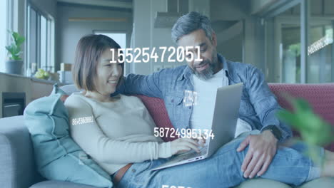 animación de números cambiando sobre una pareja biracial usando una computadora portátil