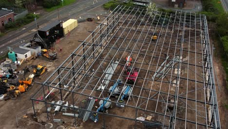 aerial lifting view over aldi grocery store building site foundation steel framework and construction equipment