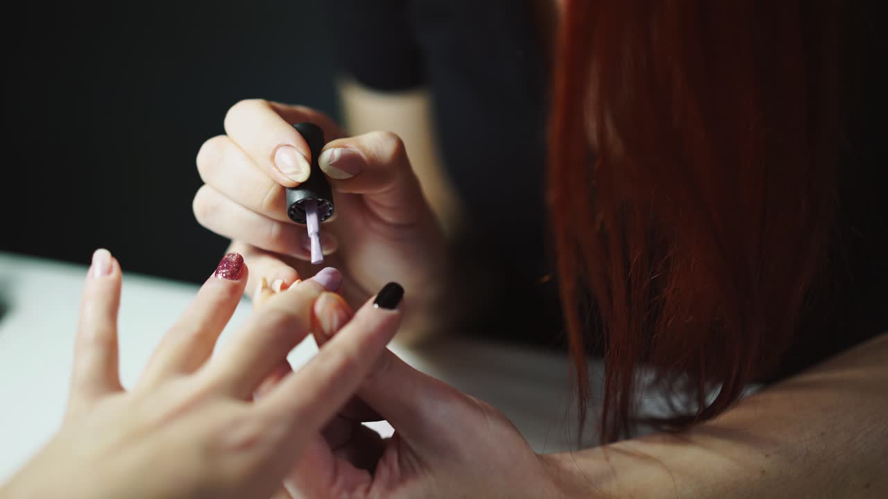 manicurist is painting nails of a woman in a beauty salon at the table. Beauty industry. Modern beauty technologies